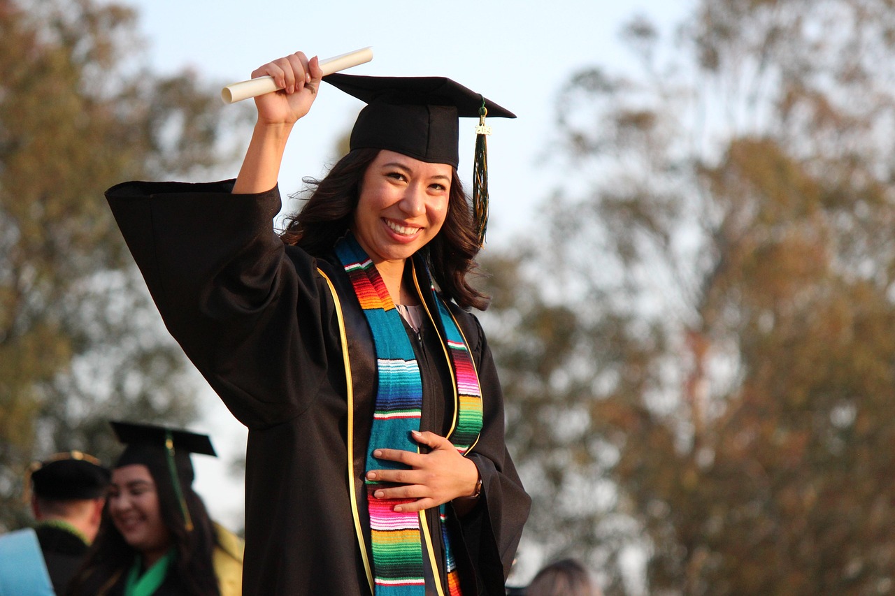 Graduada con toga y birrete sosteniendo su diploma enrollado