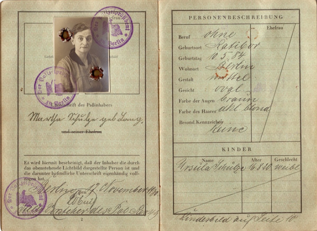 Pasaporte antiguo abierto con una fotografía en blanco y negro y sellos