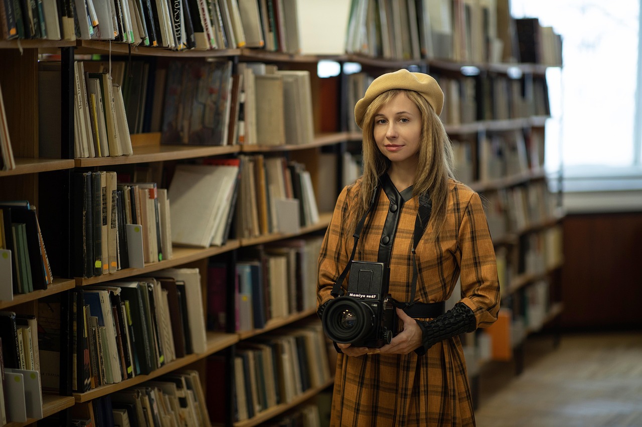 Fotógrafa con cámara de medio formato entre estanterías de una biblioteca