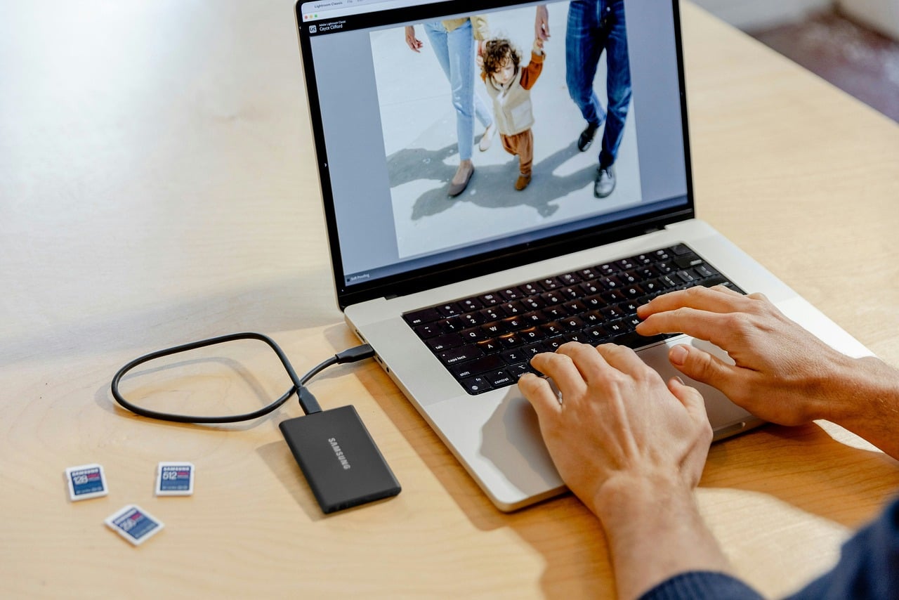 Manos editando una fotografía en un portátil junto a tarjetas de memoria