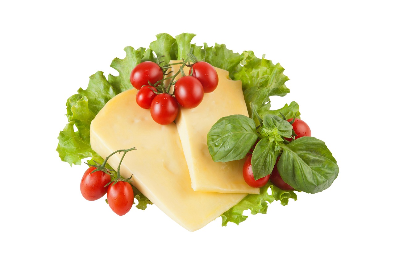 Queso, tomates cherry y albahaca recortados sobre fondo blanco