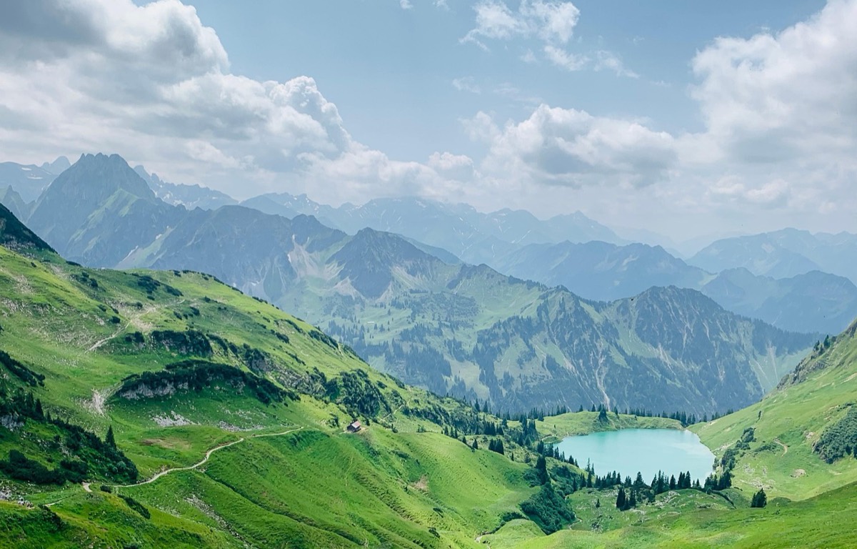 Panorámica de montañas verdes con un lago turquesa al fondo